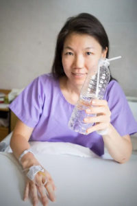 a lady in bed in hospital holding a water bottle
